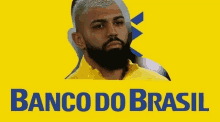 a man with a beard is sitting in front of a yellow background with the words banco do brasil .