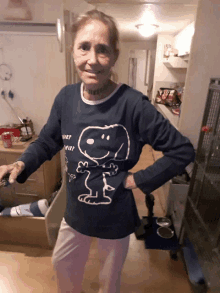 a woman wearing a blue shirt with snoopy on it stands in a kitchen