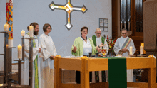 a group of people standing around a table with a cross in the background and a candle that says 100