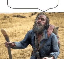 a man with a beard is holding a wooden stick in a field