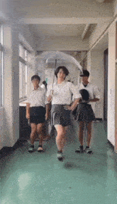 a group of people are walking down a hallway while one girl holds an umbrella