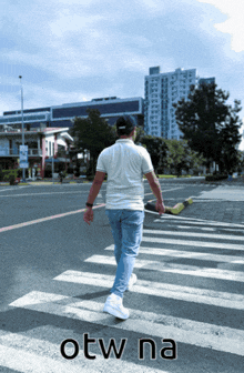 a man walking across a street with the word otw na written on the bottom