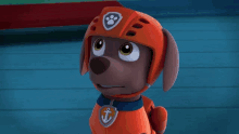 a cartoon dog wearing an orange helmet with a paw print and an anchor on his chest