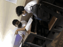 two boys wearing face masks sit at desks with a nike backpack