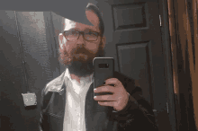 a man with a beard and glasses takes a selfie