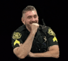 a police officer is laughing with his hand on his chin and his arms crossed .