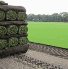 a stack of rolls of turf is sitting in front of a green field