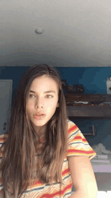 a girl with long hair wearing a striped shirt is standing in front of a bunk bed