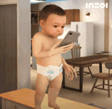 a baby in a diaper is looking at a phone