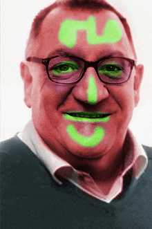 a man with glasses and green paint on his face has the letter n on his forehead