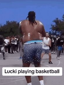 a man without a shirt is playing basketball on a court in front of a crowd .