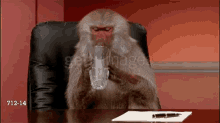 a monkey is sitting at a desk drinking from a glass with the date 712-14