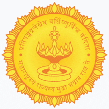 a gold colored circle with a candle in the center and the words ' सत्यम राजस्यम् ' on the bottom