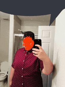 a man taking a selfie in a bathroom with a red circle on his face