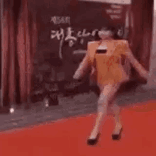 a woman is dancing on a red carpet while wearing a mask .