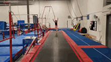 a woman is jumping on a trampoline in a gym with a sign on the wall that says " no smoking "