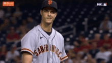 a man in a san francisco giants jersey stands on the field