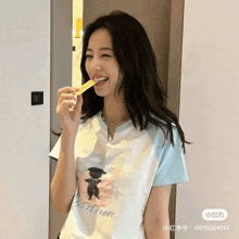 a woman wearing a t-shirt with a picture of a teddy bear on it is brushing her teeth