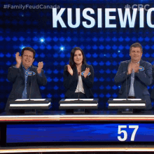 a group of people applauding in front of a sign that says " kusiewic "