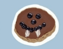 a cookie with chocolate frosting and blueberries on it looks like a monster