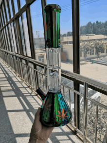 a person is holding a green bong with a leaf design on it