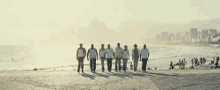 a group of people are standing on a beach with a city in the background