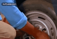 a person is changing a tire on a car with their hands .