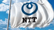 a white and blue flag with the ntt logo on it is waving in the wind .