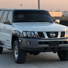 a white nissan suv is parked on a brick pavement