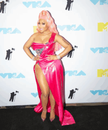 a woman in a pink dress stands in front of a wall that says mtv on it