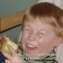 a young boy is making a funny face while holding an apple and says " you want to get into parking lot striping ? "