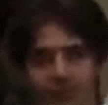 a blurry picture of a man 's face with glasses and long hair .