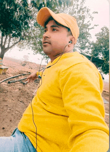 a man wearing a yellow sweater and a yellow hat is listening to music with headphones