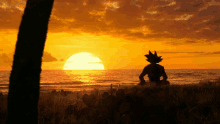 a silhouette of a person sitting on a beach watching the sunset