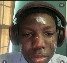 a young man wearing headphones has a tear running down his cheek