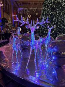 a group of reindeer are sitting on a table in front of a christmas tree