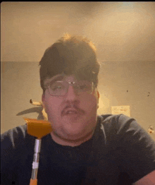 a man with glasses and a mustache is holding a cleaning brush .