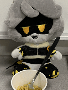 a stuffed animal sitting next to a bowl of noodles with a spoon