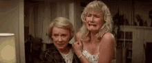 two women are crying in a living room .