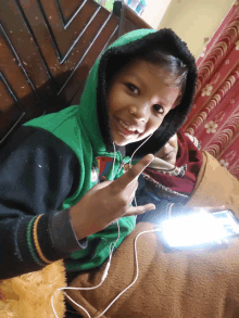 a young boy wearing headphones and a green hoodie is smiling for the camera