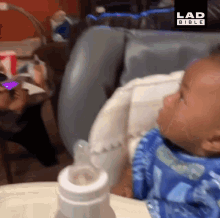 a baby is drinking from a bottle with the lad bible logo on the bottom right