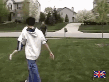 a man in a white hoodie is walking on a lush green lawn with a british flag in the foreground