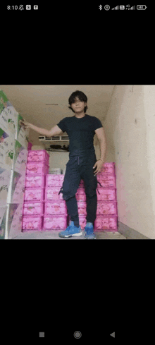 a man in a black shirt is standing in front of a stack of pink boxes with chinese characters on them