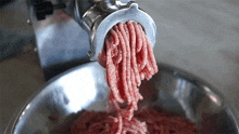 a meat grinder is grinding meat into a bowl