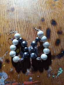 a pair of black and white pearl earrings sit on a wooden table