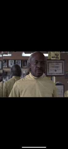 a man in a yellow shirt stands in front of a mirror in a gym