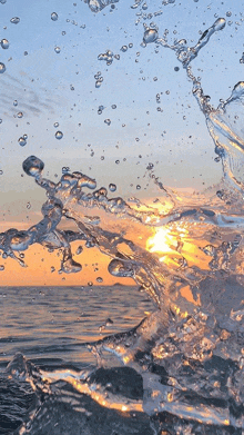 a splash of water in the ocean with the sun behind it