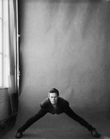 a black and white photo of a man stretching his arms and legs