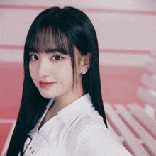 a girl with long black hair and bangs wearing a white shirt