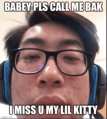 a young man wearing glasses and headphones is making a funny face and saying i miss u my lil kitty .